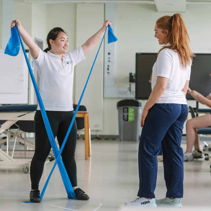 two female students practising with blue resistant bands