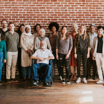 A diverse group of people standing in front of a brick wall
