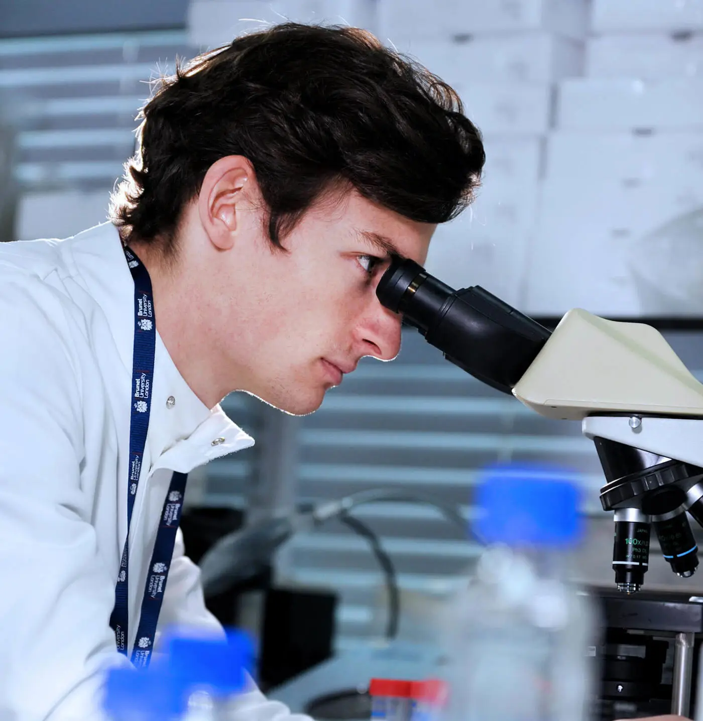 Male student looking through microscope in a bioscience lab