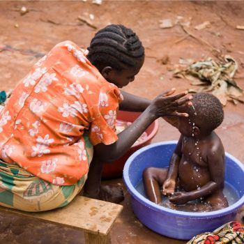 A woman bathing a child outdoors