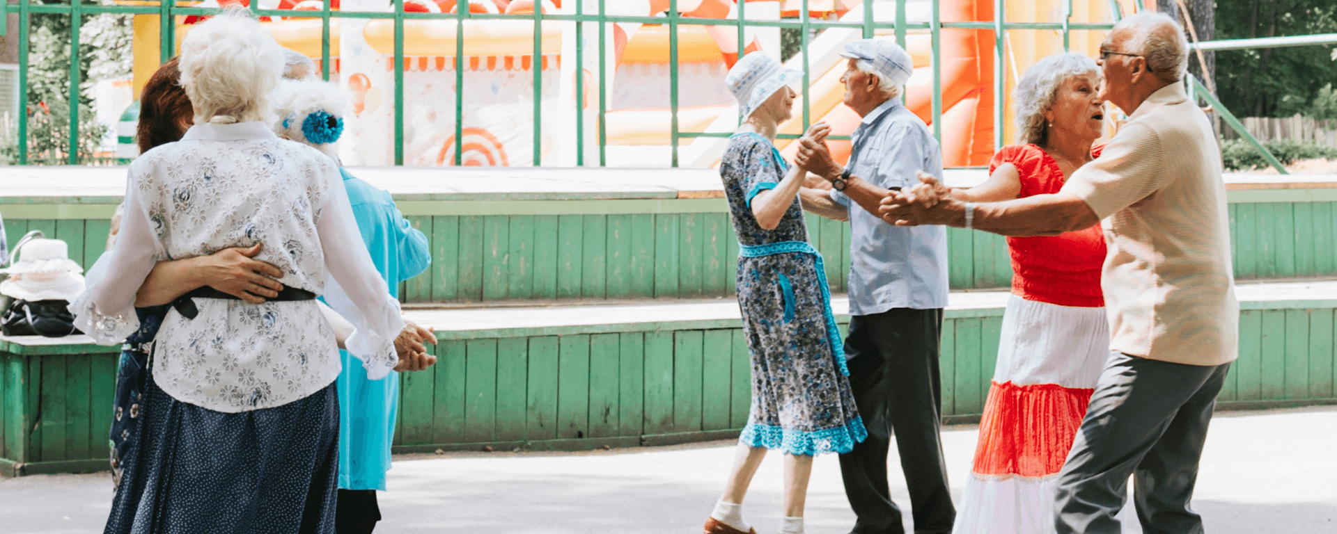 Elderly couples dance joyfully outdoors, surrounded by colorful decorations and a vibrant atmosphere