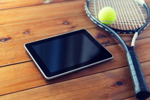 close up of tennis racket with ball and tablet pc