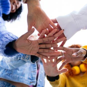 A group of young people joining hands together.