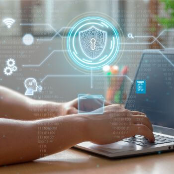 Hands typing on a laptop with futuristic cybersecurity and technology holograms overlaying the image.