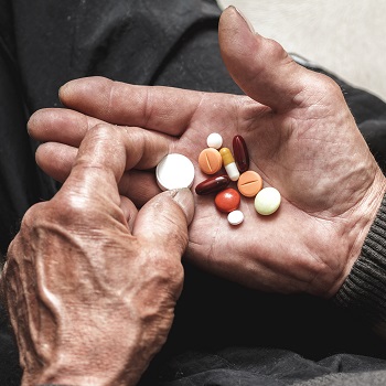 old man hands holding many pills of medication