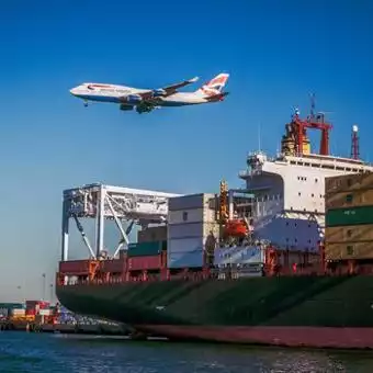 plane flying over cargo ship