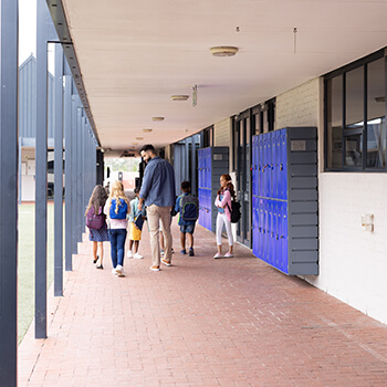 Male teacher and children in elementary school corridor