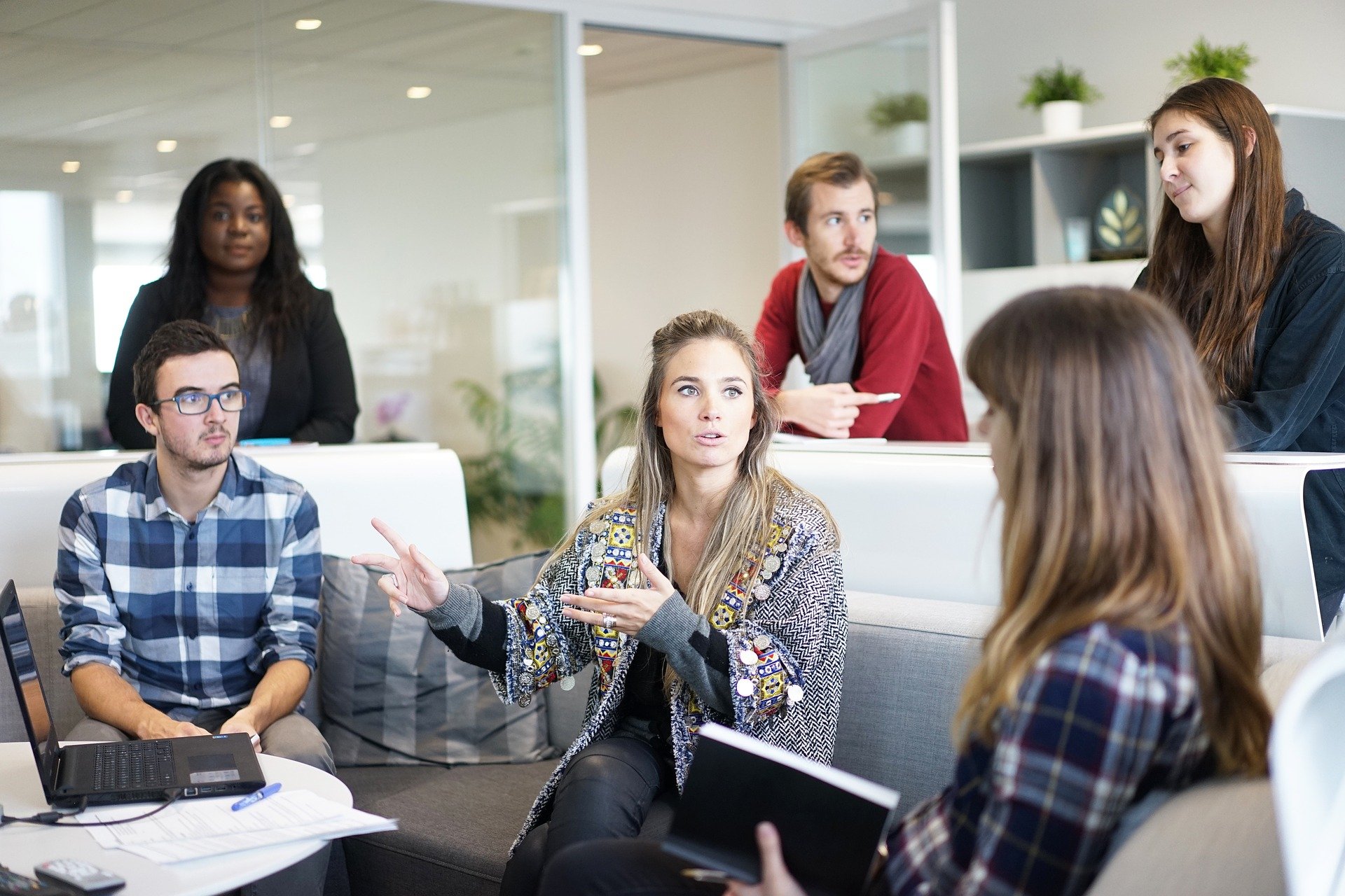 People of diverse genders and ethnicities gathered in a office meeting room, and have a discussion.