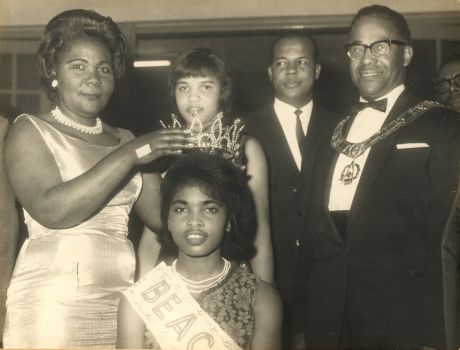 old image of black english people placing tiara on girls head