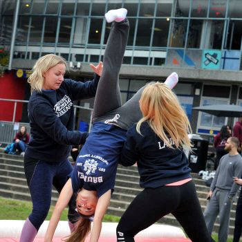 female coaches teaching acrobatics to female student and supporting her whilst she perfroms a backflip