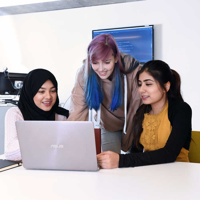 image of 3 students looking at the laptop