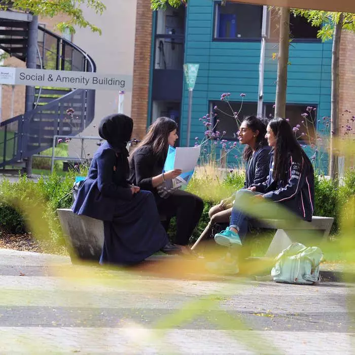 4 students sitting on a bench outside of student accommodation
