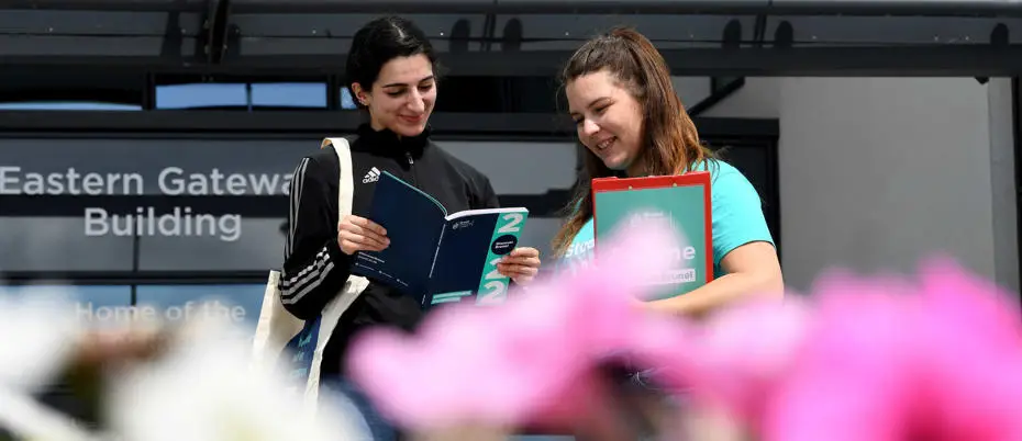 student reading a book in front of a building