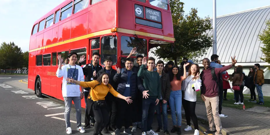 Group of students in front of a red bus. 