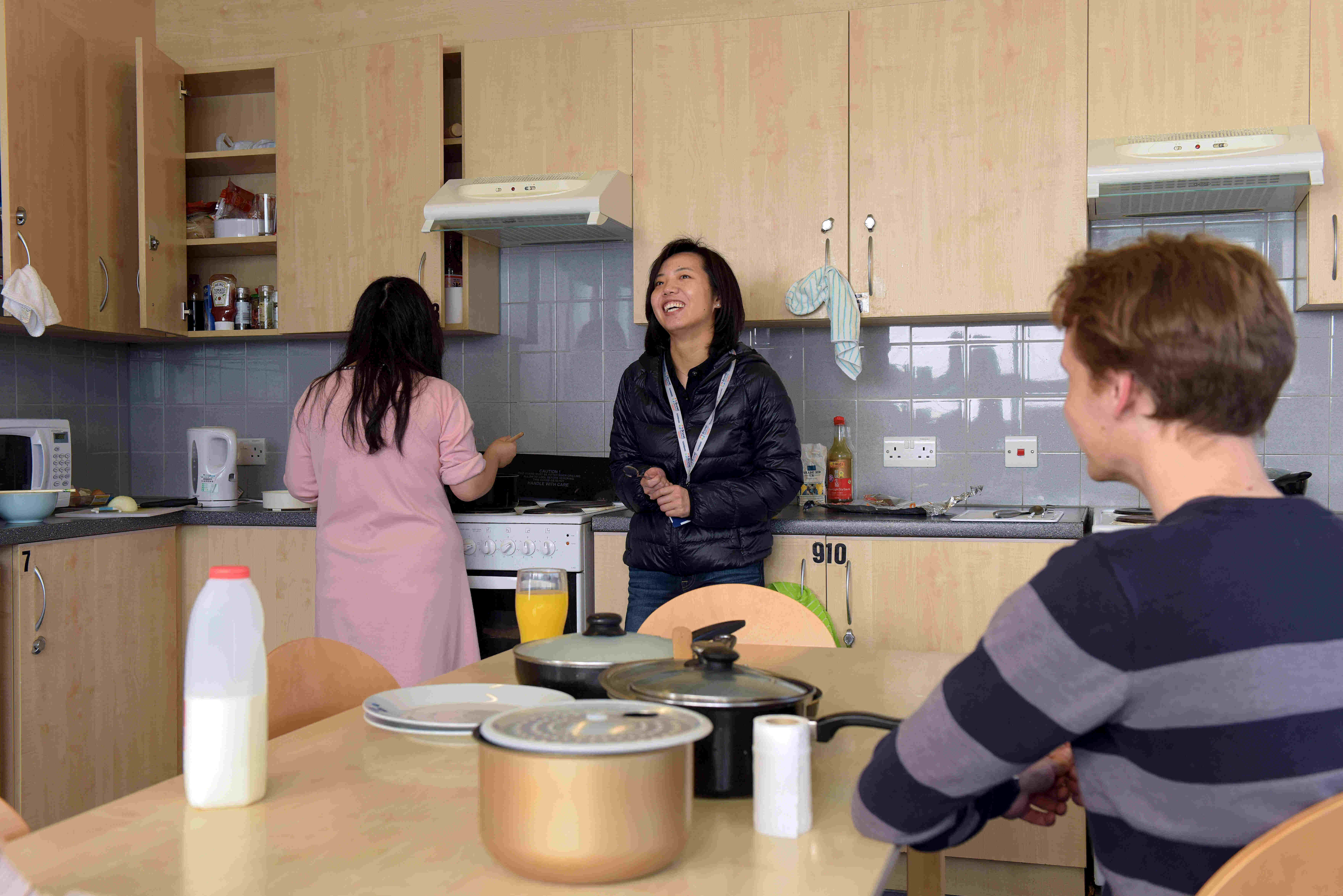Three students congregating in the kitchen in Brunel's accommodation.