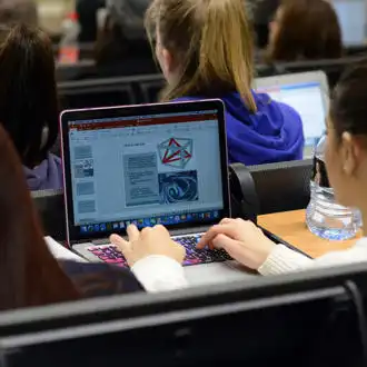 female student making notes on her laptop during lecture