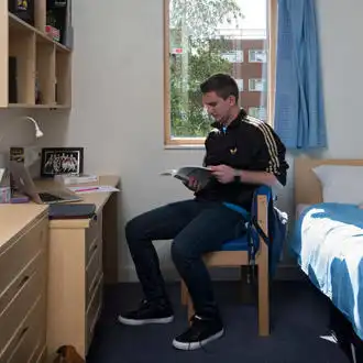 Male student sitting at his desk in university accommodation