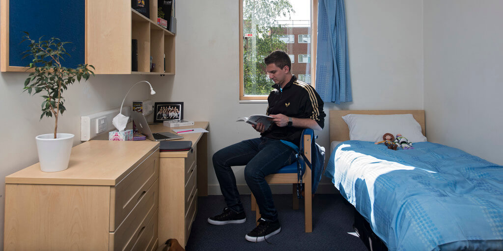 Male student sitting at his desk in university accommodation