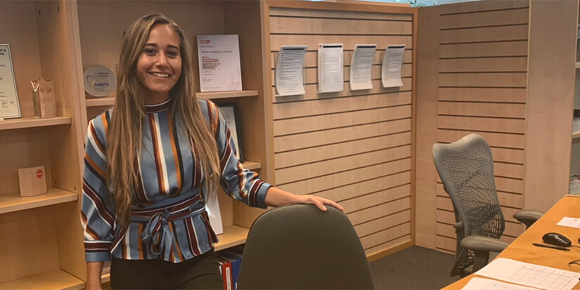 Sabrina standing at her desk in the Professional Development Centre