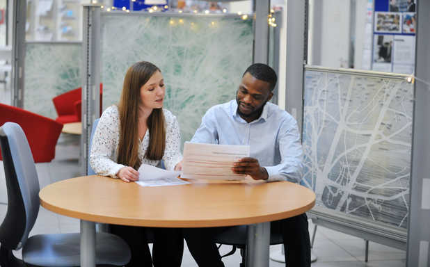 A man and a woman sitting at a table reading documents.