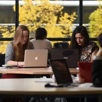 students studying in the library with an autumn view in the background