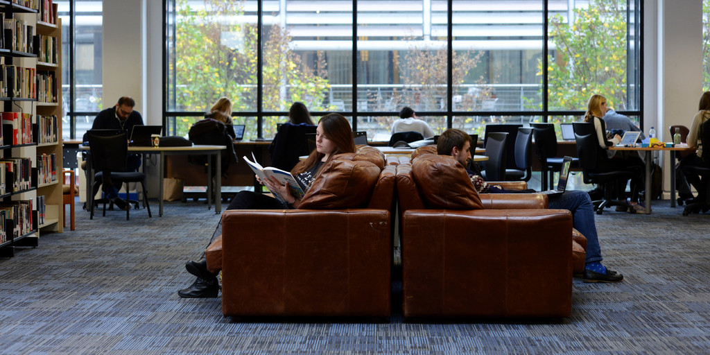two students reading in the library autrium