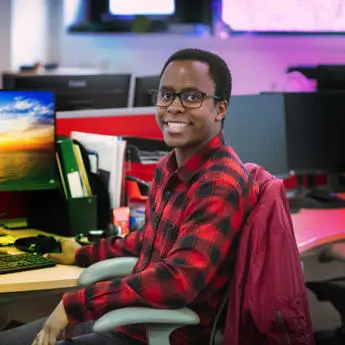 man sitting in front of computer desk smiling into camera