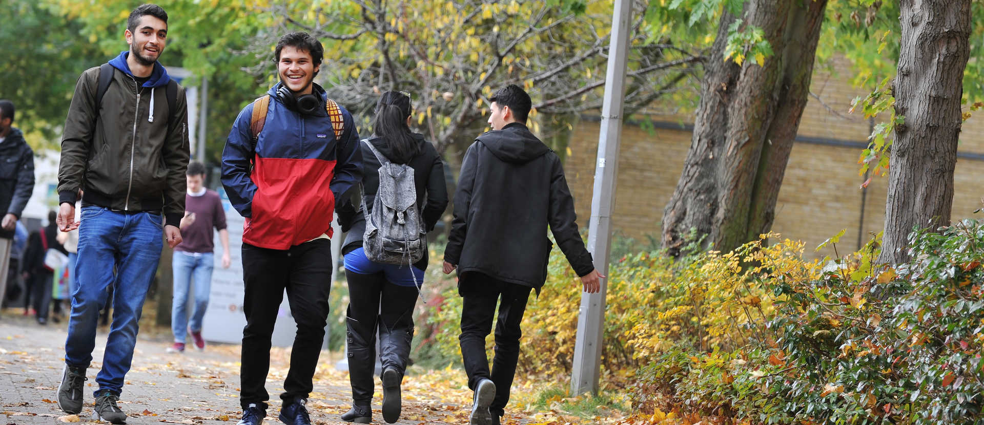 2 international students walking through campus talking and smiling.