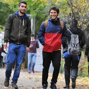 2 international students walking through campus talking and smiling.