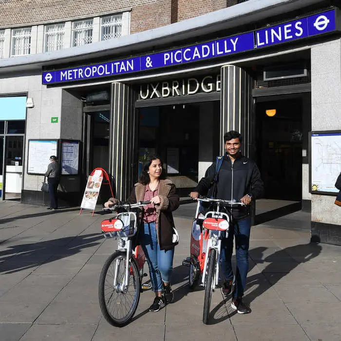 two students with bikes in front of uxbridge underground station