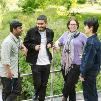 group of students chatting on a bridge by River Pinn at Brunel University London campus