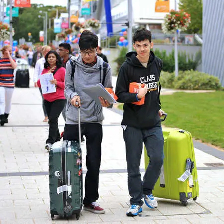 two new students walking across campus with their suitcases