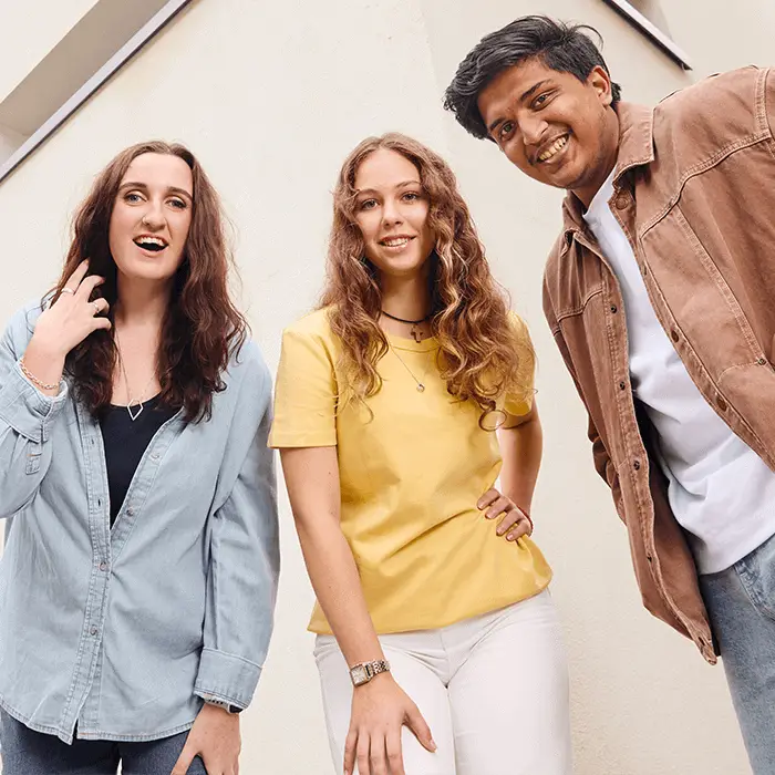 Three young adults pose together outdoors