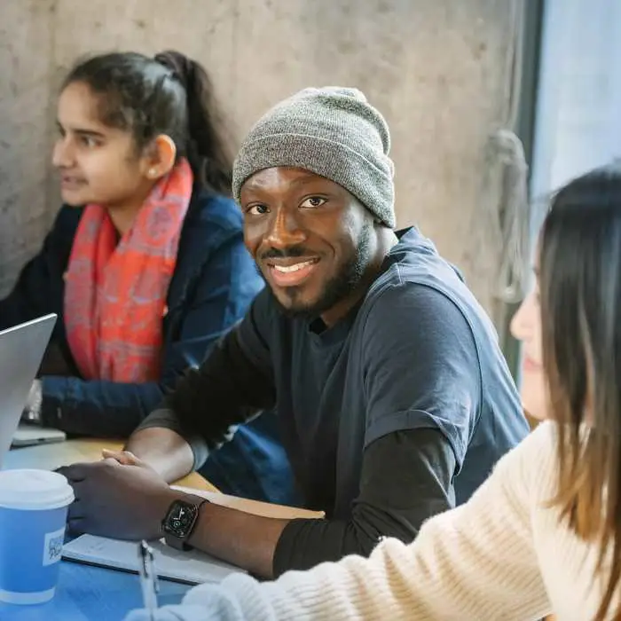 man in a hat in a study group smiling into the camera
