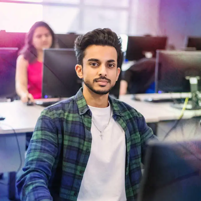 man sitting in a computer lab looking into the camera