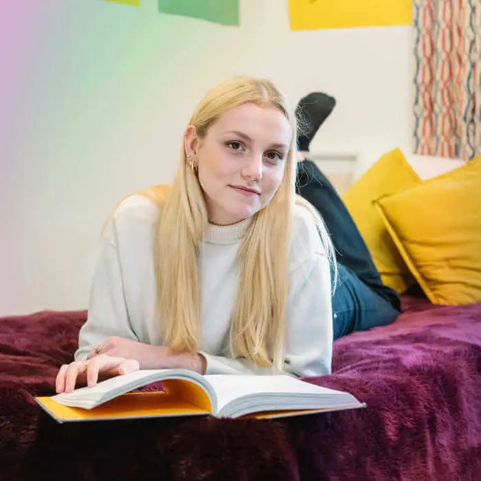student reading a book on a bed