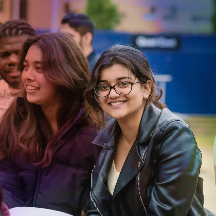 woman sitting in a park with friends smiling into the camera
