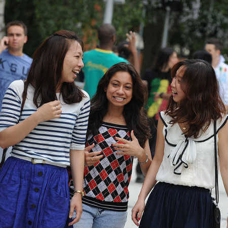postgraduate study international students walking through campus smiling and laughing