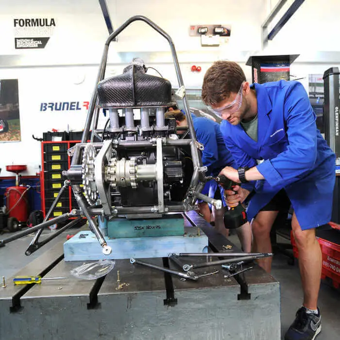 Person in blue overalls working on a high-performance engine in a workshop