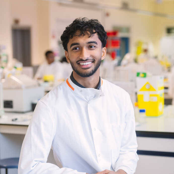 a-brunel-student-in-a-lab-coat-stands-in-a-bright-lab-filled-with-equipment
