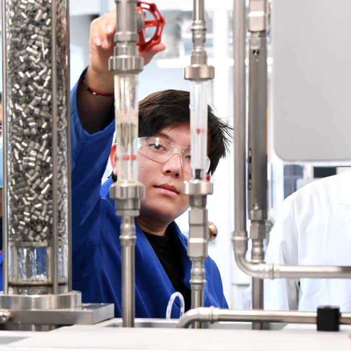 Brunel Chemical Engineering student in lab coat and glasses working in the lab