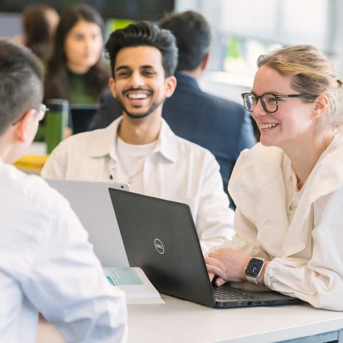 Two male and one female student seated on a table and talking