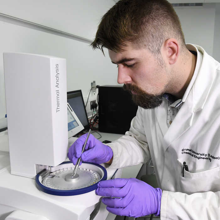 Male student doing thermal analysis on a machine