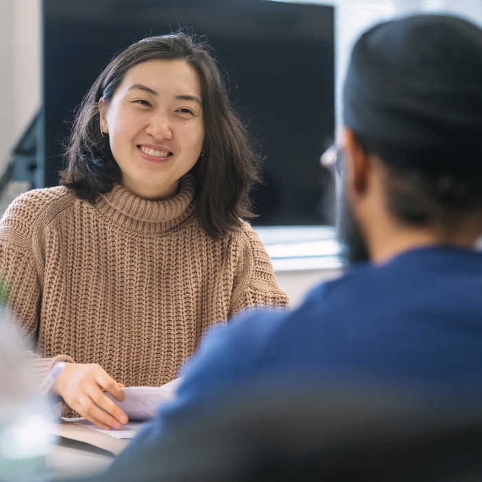 Female student smiling at a male student whilst sitting on a table