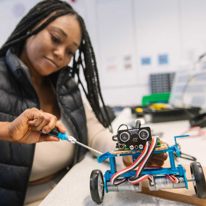 Female student working on a vehicle in an electronic engineering lab