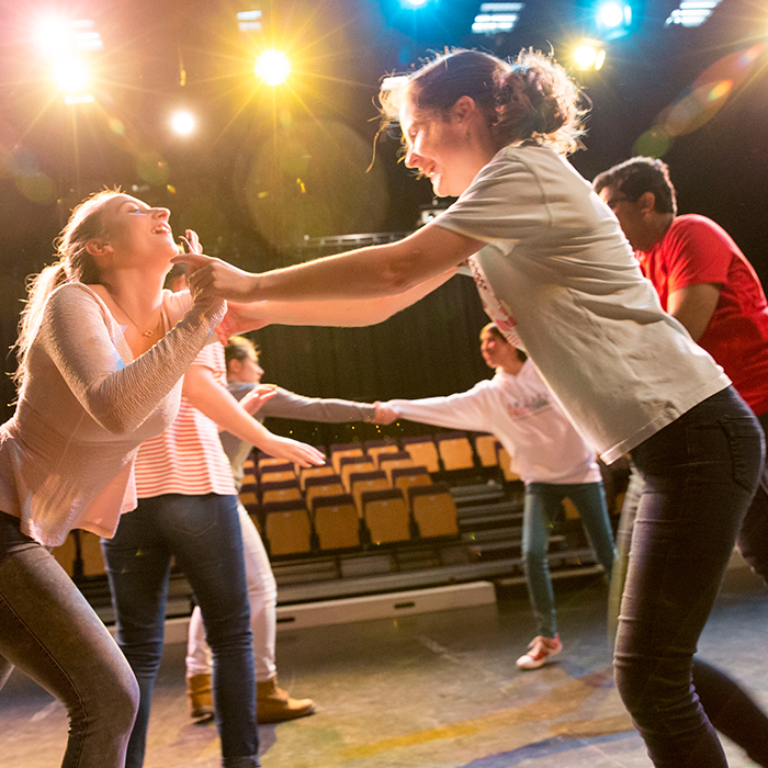 students performing theatre on stage and holding hands